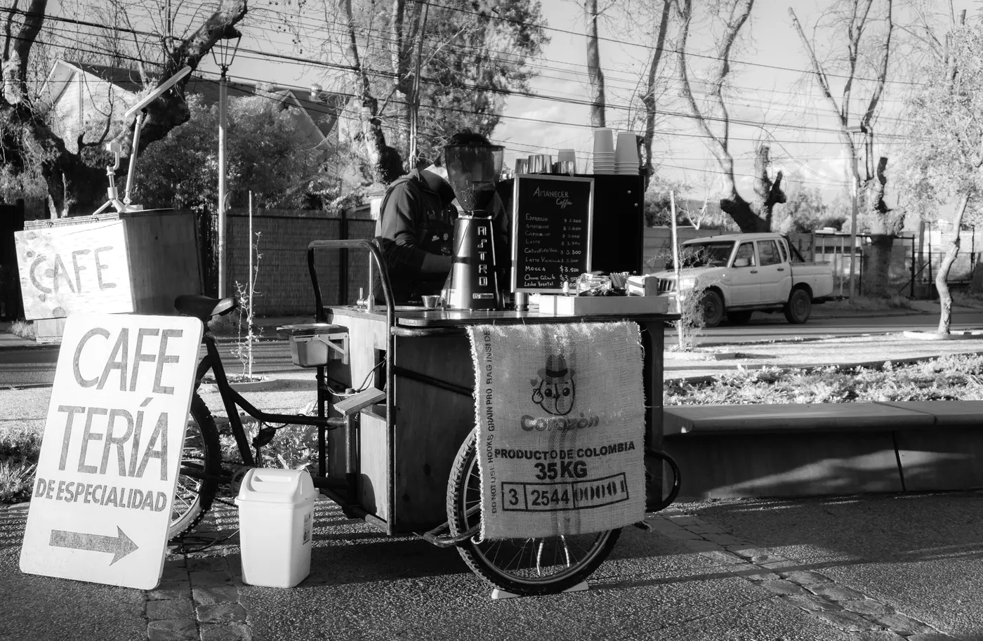 El triciclo cafetería y su letrero, en blanco y negro.