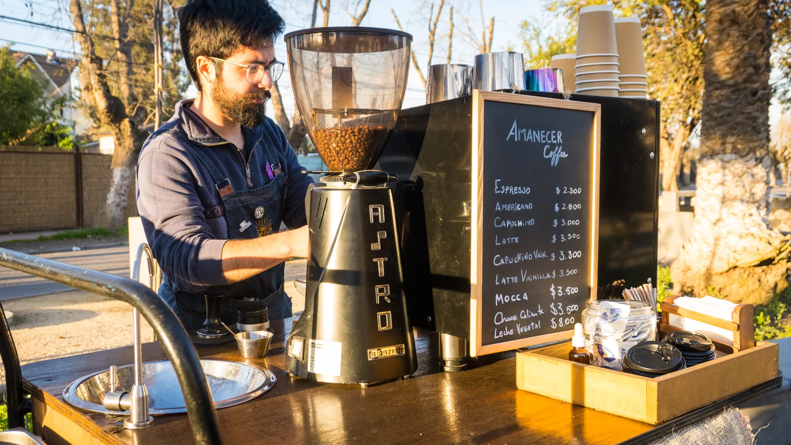 Montaje de la cafetería con molino, pizarra de la carta y vasos preparados para atender.